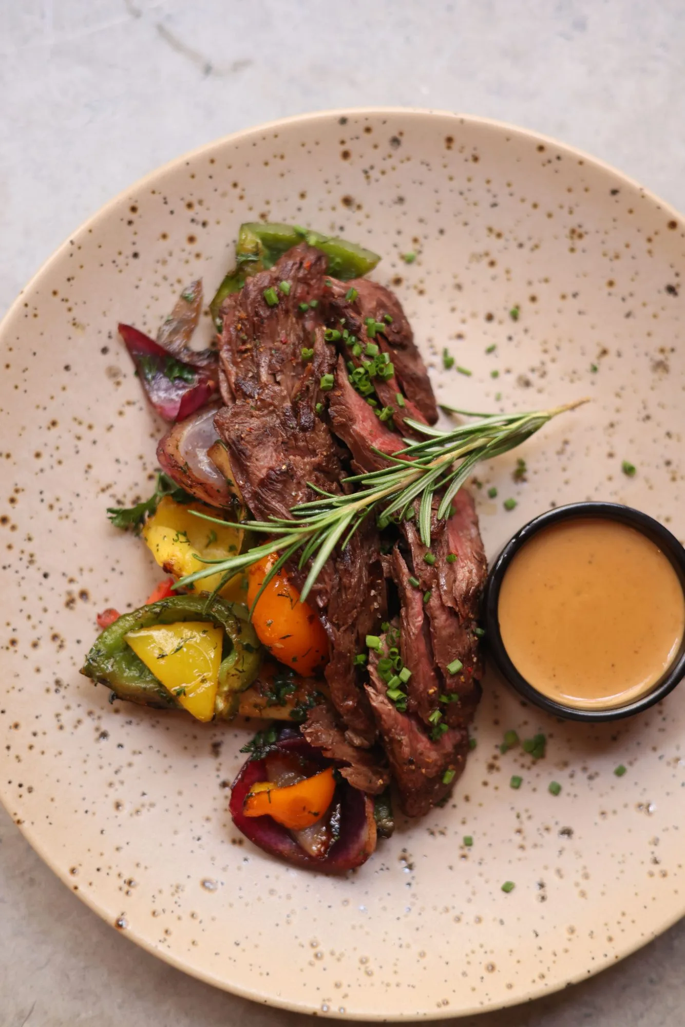 Piatto di carne a fette con verdure e salsa, visto dall'alto
