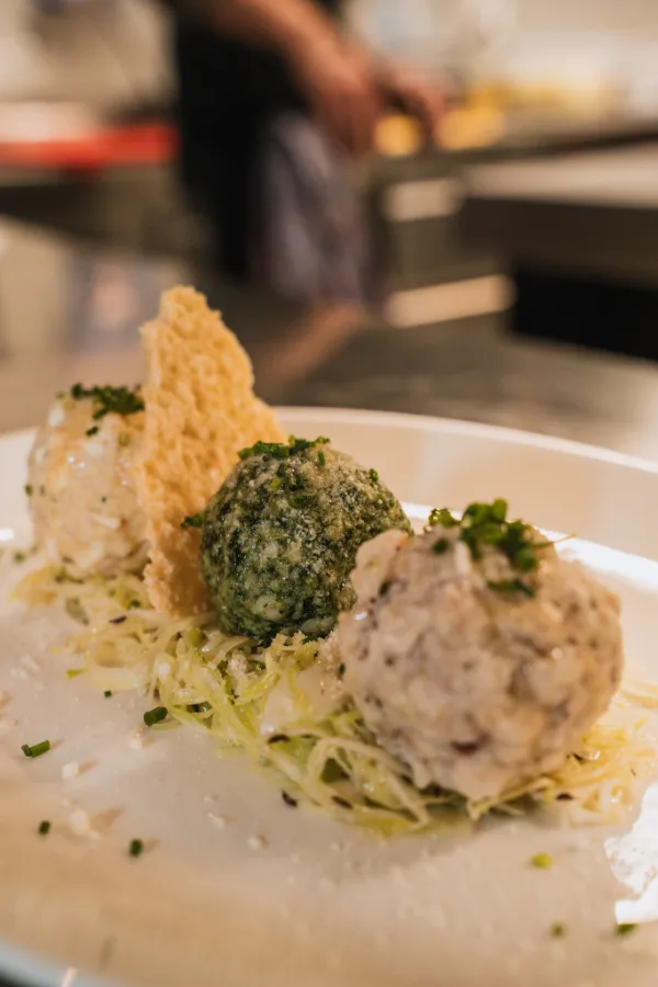Tris di canederli su insalata di cavolo con cialda di formaggio.