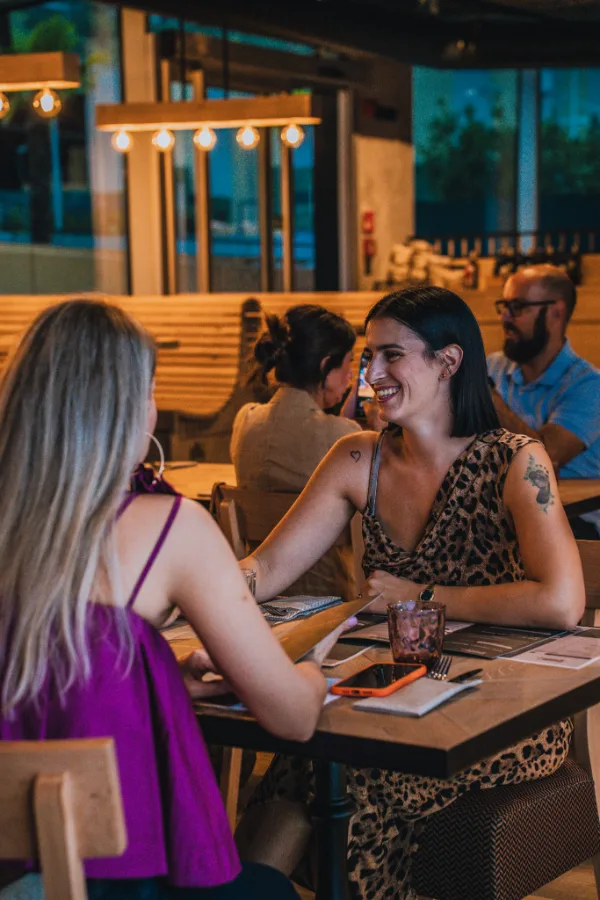 Due amiche sorridenti a cena in un ristorante.